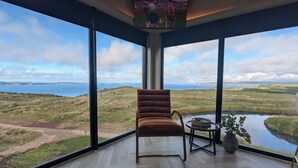 Une pièce dotée de grandes fenêtres donnant sur la mer et le paysage.