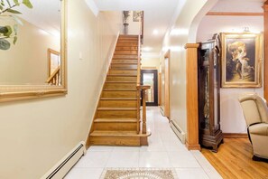 Staircase leads to an upper floor, flanked by a mirror and a grandfather clock.