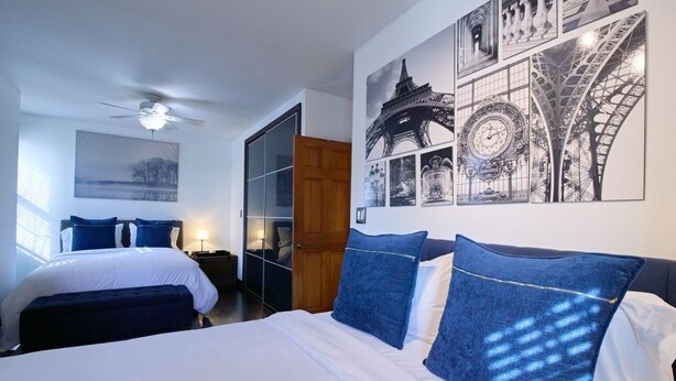 Een hotelkamer met een bed, een garderobe, een spiegel en een muur met afbeeldingen van de Eiffeltoren.