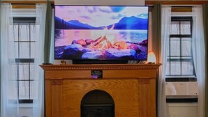 Een woonkamer met een open haard, een televisie, een glazen tafel en een bank.