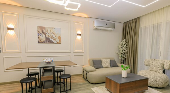 A modern living room with a dining table, sofa, and decorative plants. - Sokon Residence Madinaity (New Cairo)