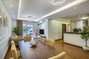 A modern living room with a dining table, sofas, and a TV.