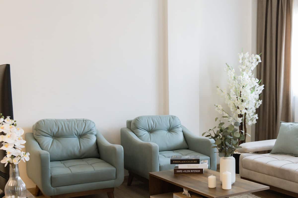 A living room with two armchairs, a sofa, a coffee table, and a vase with flowers.