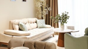 Un salon moderne avec un canapé, une table ronde en bois et un fauteuil vert.