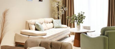 A modern living room with a sofa, a round wooden table, and a green armchair.