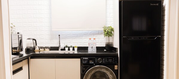 Uma cozinha compacta com máquina de lavar, cafeteira e pia pequena.