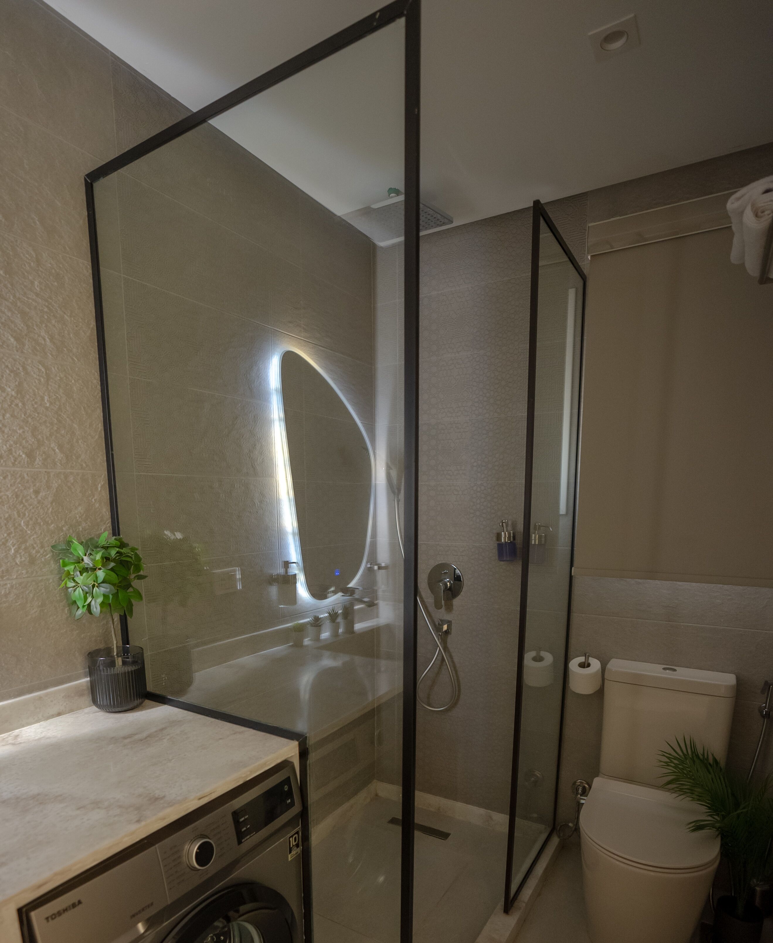 Un baño moderno con cabina de ducha de vidrio, lavabo empotrado y retrete.