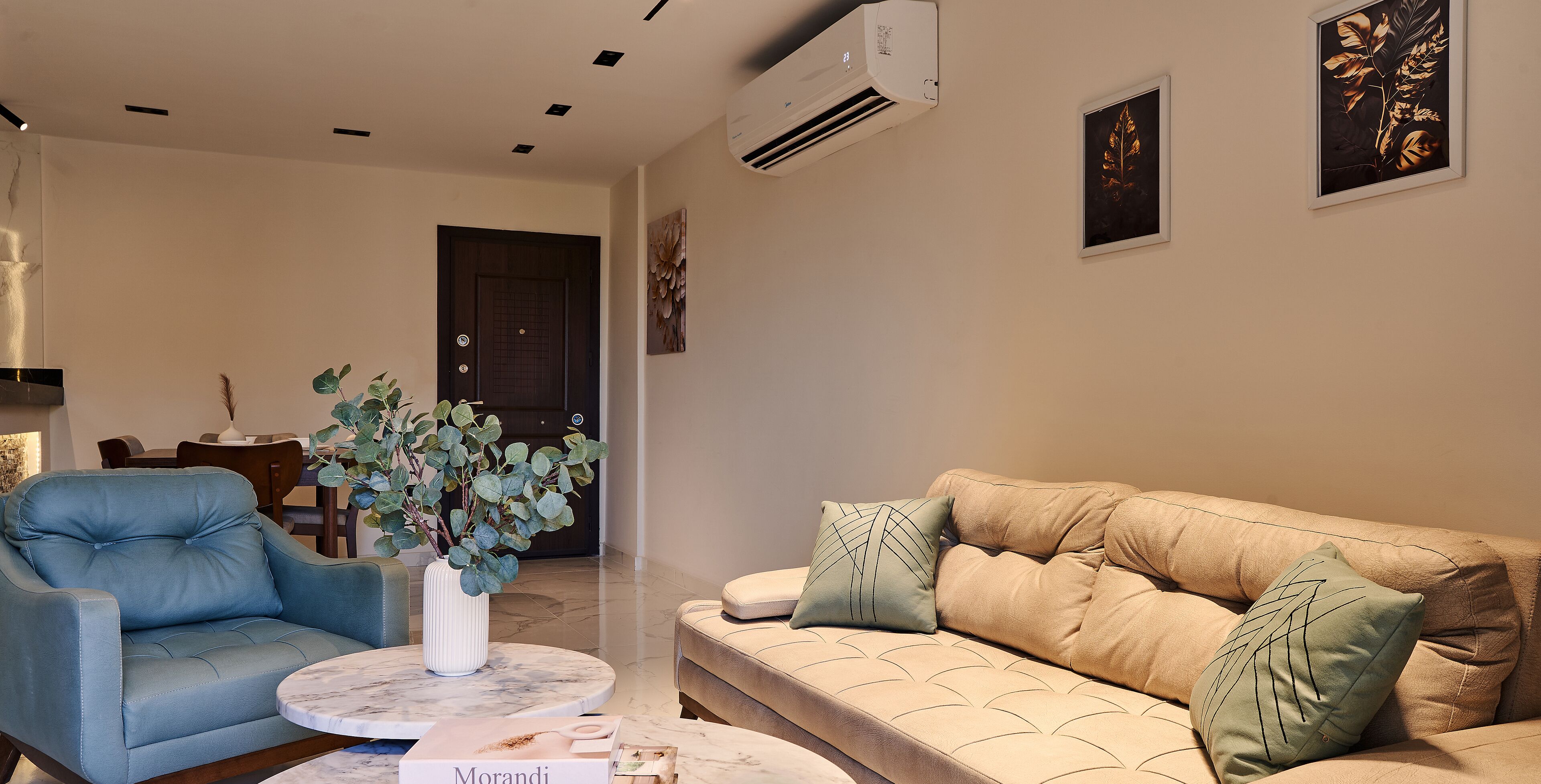 A living room with a blue armchair, beige sofa, and a round coffee table.
