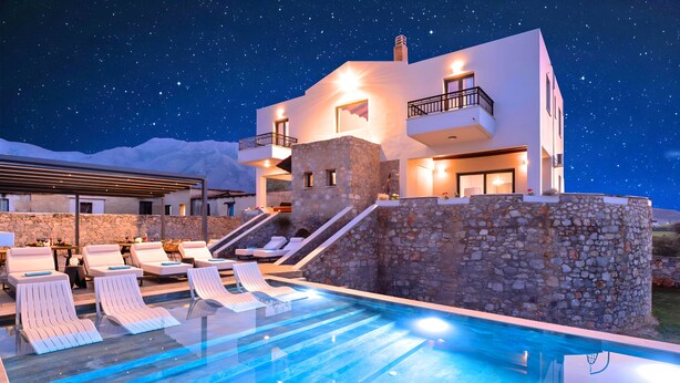Un hôtel moderne doté d’une piscine, de murs en pierre et offrant une vue sur un ciel étoilé.