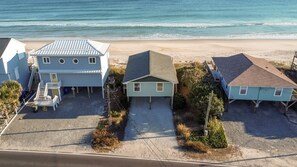 Une propriété située en bord de mer, comprenant trois maisons, chacune ayant un style de toit distinct et un petit jardin à l’avant.