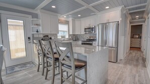 Una cocina moderna con armarios blancos, electrodomésticos de acero inoxidable y una isla central con asientos.