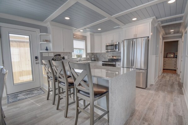 A modern kitchen with white cabinetry, stainless steel appliances, and a central island with seating.