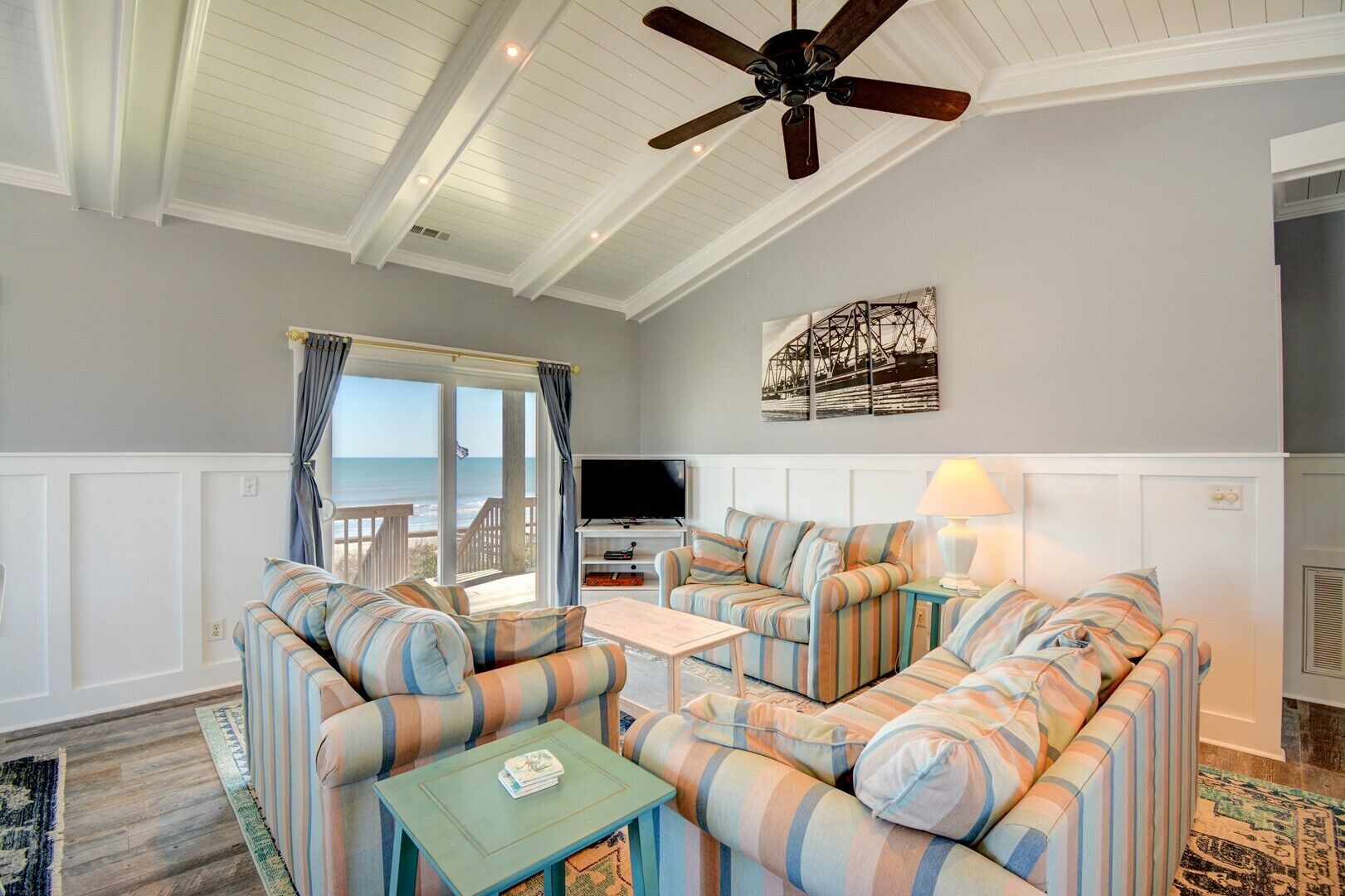 A living room with striped sofas, a television, and a ceiling fan.
