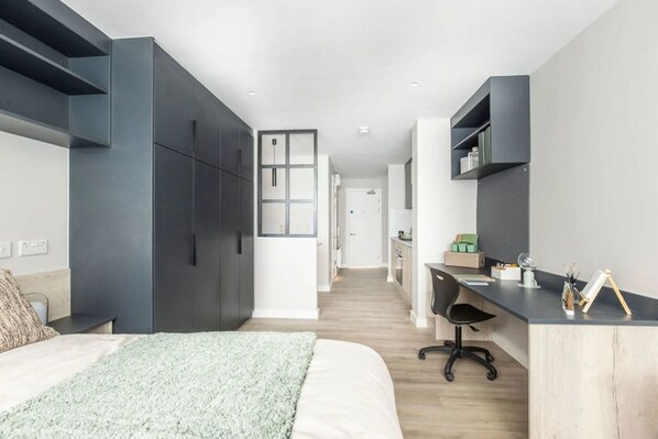 Et moderne soveværelse med en stor seng, et skrivebord og en garderobe.