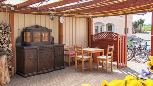 Un porche cubierto con una mesa y sillas de madera, un mueble de madera oscura y una bicicleta estacionada afuera.