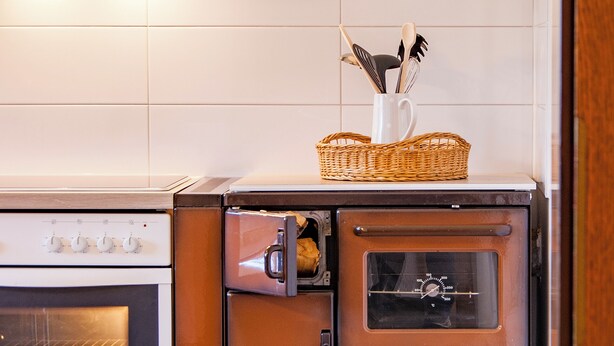 Una cocina con un horno blanco, un horno marrón y un microondas.