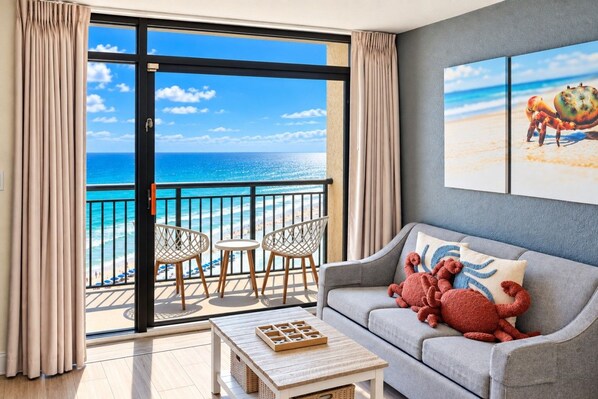 Playful crab decor and a coastal tone in this 1BR getaway`s living room, furnished with a comfy sofa and balcony access.