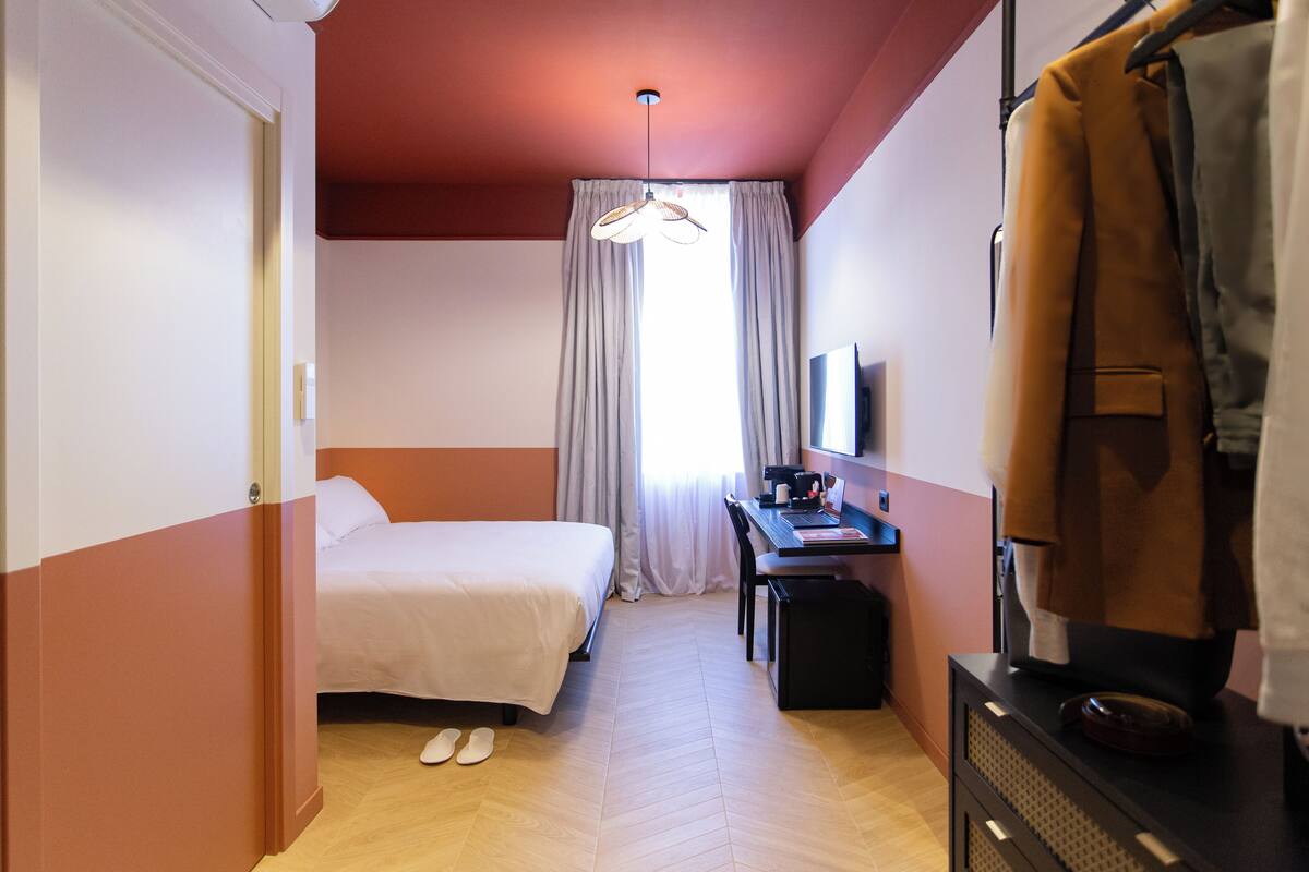A hotel room with a bed, desk, chair, and a television.