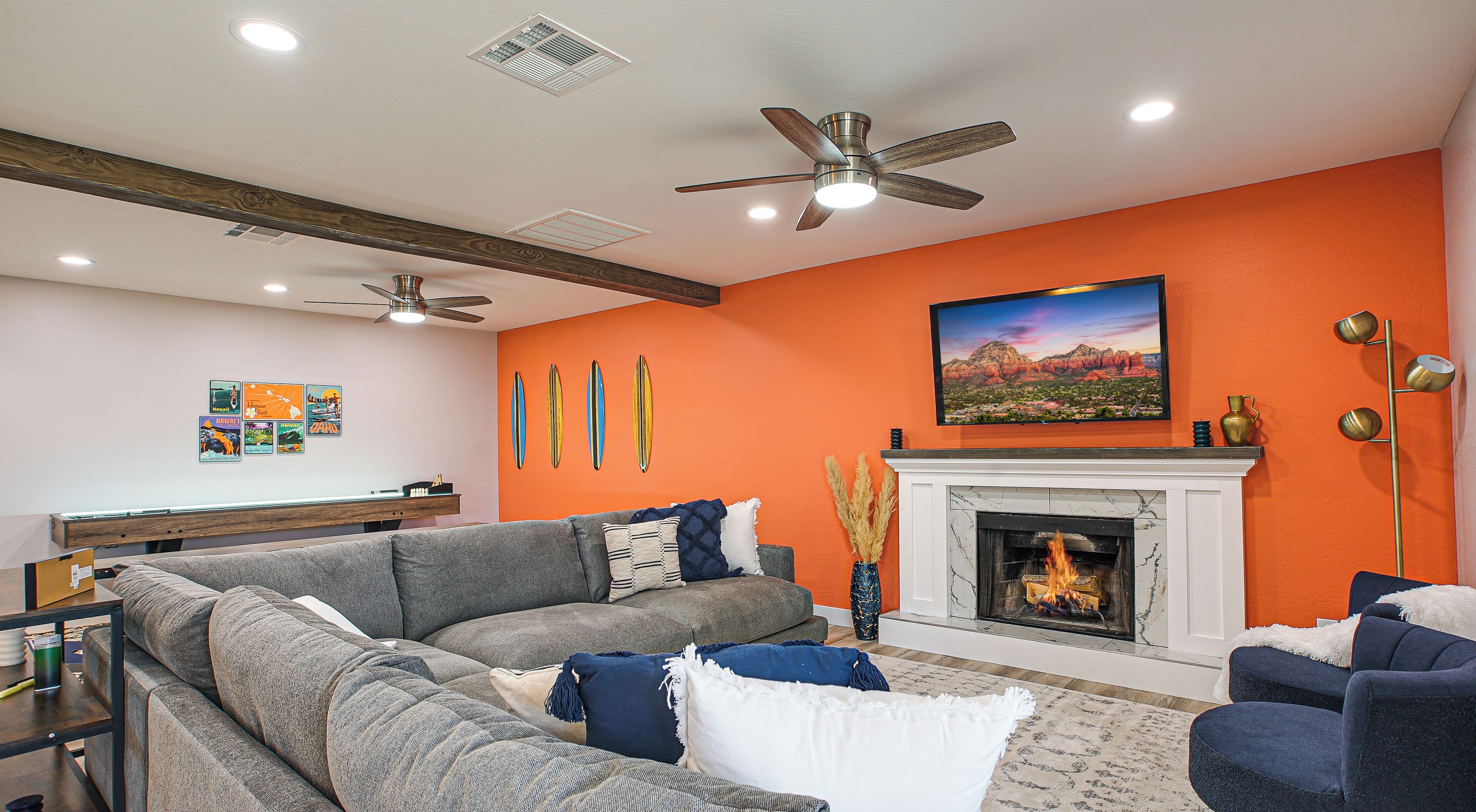 A living room with a fireplace, a sofa set, a ceiling fan, and a wall-mounted TV.