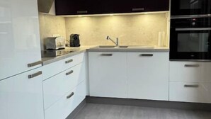 A modern kitchen with white cabinets, a black countertop, and a stainless steel sink. - 3-ROOM APARTMENT NEAR TOWN CENTER (Obernai)