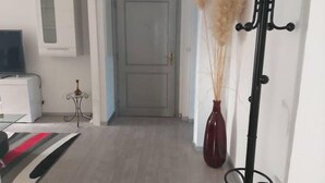 A hallway with a coat rack, a door, and a vase with dried plants. - 3-ROOM APARTMENT NEAR TOWN CENTER (Obernai)