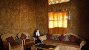 Ein Zimmer mit einer Wand aus Holz mit Fischgrätmuster, einer Sofagarnitur, zwei Sesseln und einem Couchtisch mit Glasplatte.