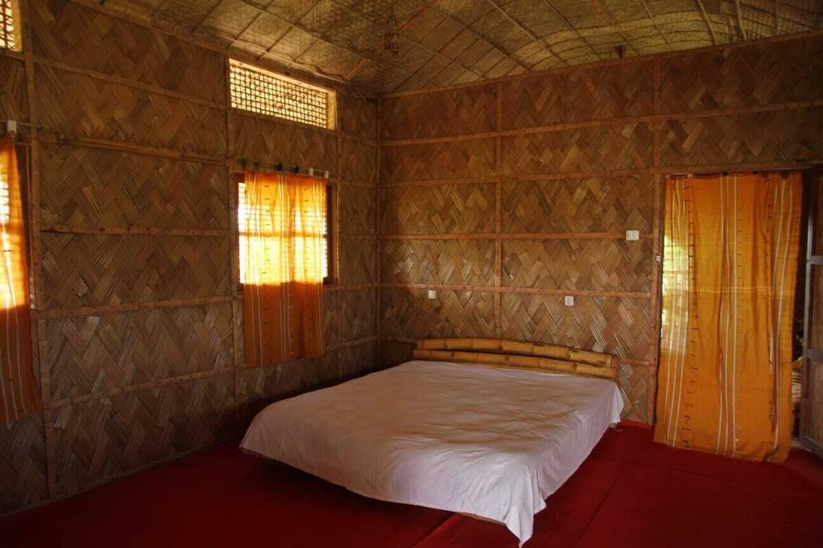A room with a bed, wooden walls, and a red carpet.