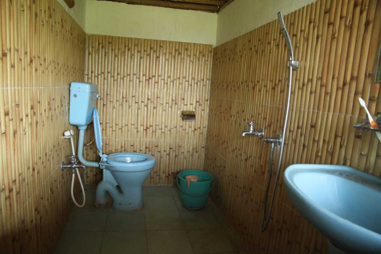 A small bathroom with bamboo walls, a toilet, a shower, and a sink.