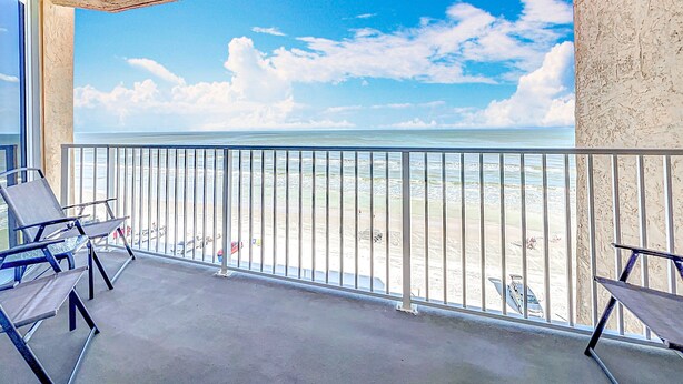 A balcony with a view of the beach and ocean.