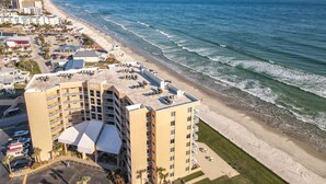 A high-rise hotel with multiple balconies overlooking a beach.