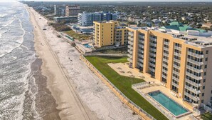 A beachfront hotel with multiple floors, a swimming pool, and a beach view.