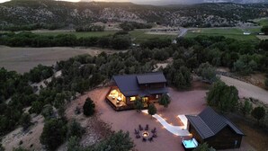 Una cabaña con una amplia terraza, una fogata y una piscina.