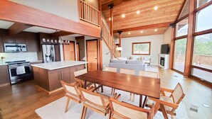 Una cocina amplia con electrodomésticos modernos, un comedor con mobiliario de madera y un gran ventanal con vistas al exterior.