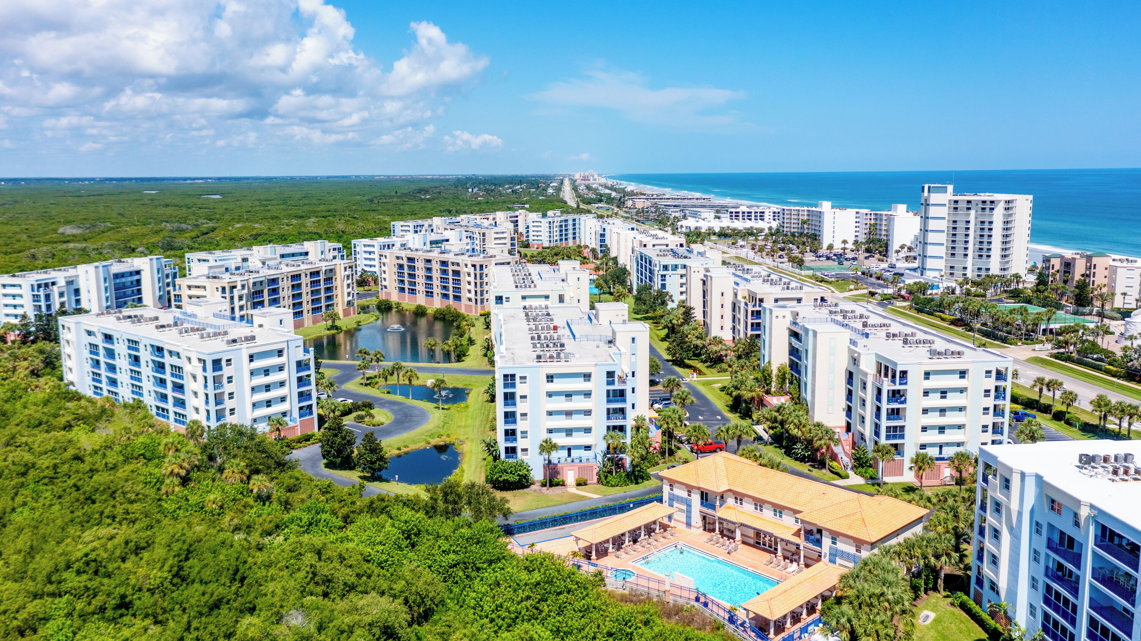 A high-rise hotel with multiple floors, a swimming pool, and a view of the ocean.