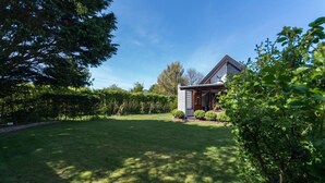 A house with a well-maintained lawn and a wooden deck. - Bungalow in North Holland Coast (Sint Maartensvlotbrug)
