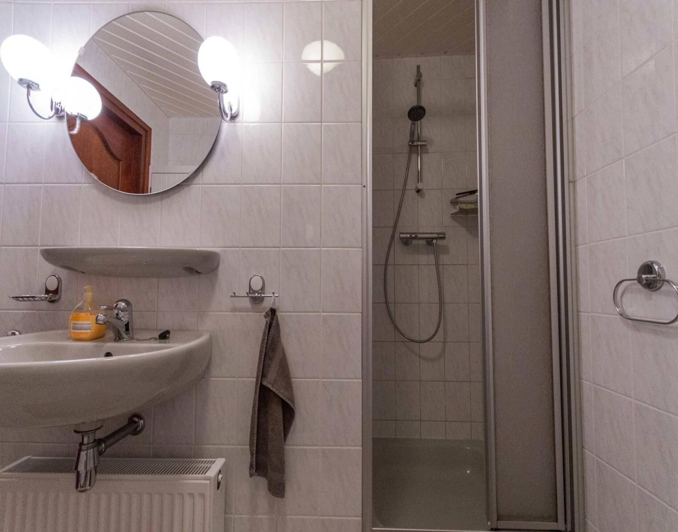 A bathroom with a sink, mirror, and shower.