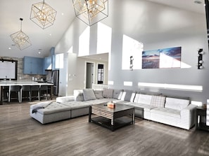 A modern living room with a sectional sofa, a coffee table, and pendant lights.