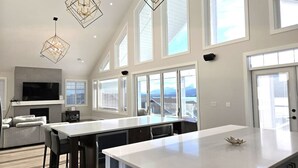 A modern kitchen with a large island, pendant lights, and a view of the mountains. - Sky-View Cottage - 5 Bedroom View home 265 (Osoyoos)