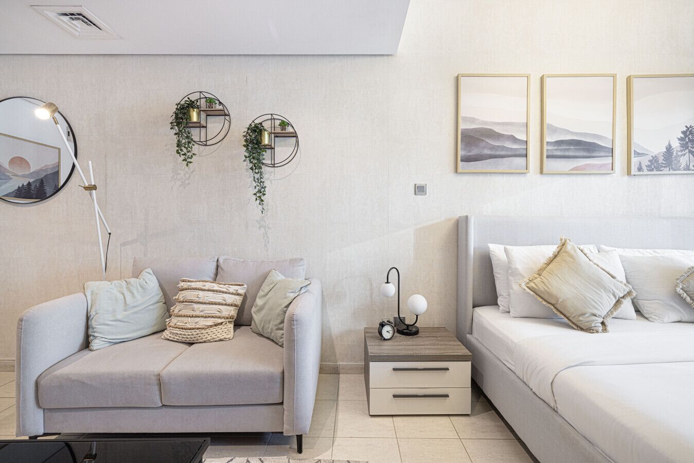 Een moderne slaapkamer met een grijze bank, een nachtkastje met lamp, en een bed met wit beddengoed.