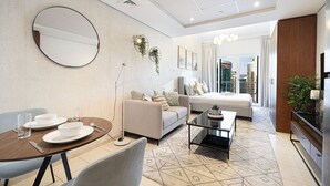 A modern hotel room with a dining area, a sofa, a bed, and a view of the city. - Lake View Studio near Marina with Pool, Balcony and Gym (Dubai)