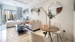 A modern hotel room with a bed, a sofa, a dining table, and a large window with a city view. - Lake View Studio near Marina with Pool, Sauna and Gym (Dubai)