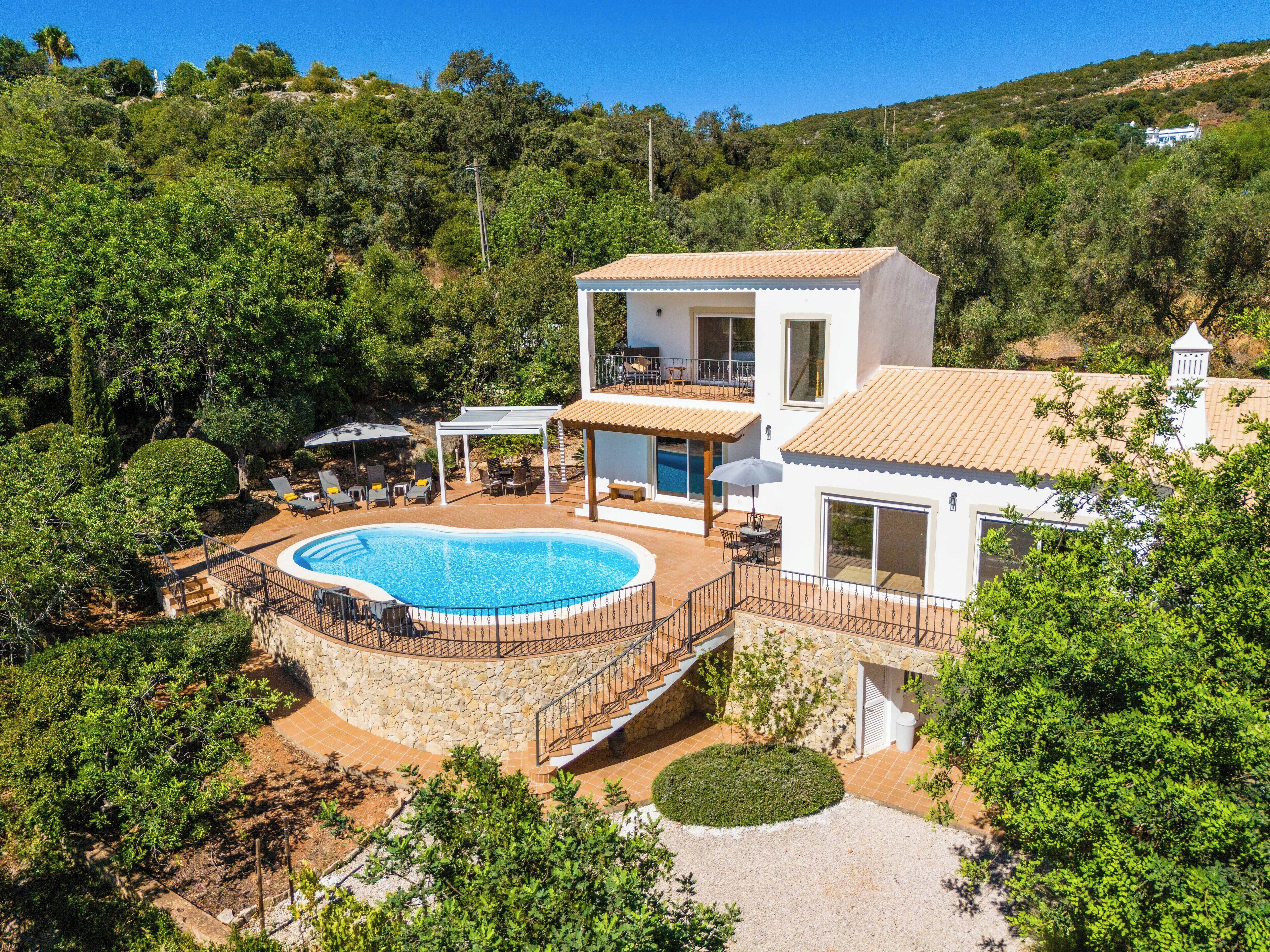Une villa à deux étages dotée d’une piscine, d’un espace salon extérieur et d’un escalier en pierre.