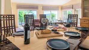 Un espace repas doté d’un comptoir en marbre, d’une bouteille de vin, d’une miche de pain et d’une variété de fruits et de fromages.