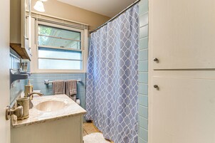 A bathroom with a sink, mirror, towel rack, and a window with a view of trees.