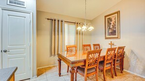 A dining area with a wooden table and chairs, a chandelier, a white door, and a window with curtains. - 5 Mi to Downtown - Peaceful Home in Casa Grande (Casa Grande)