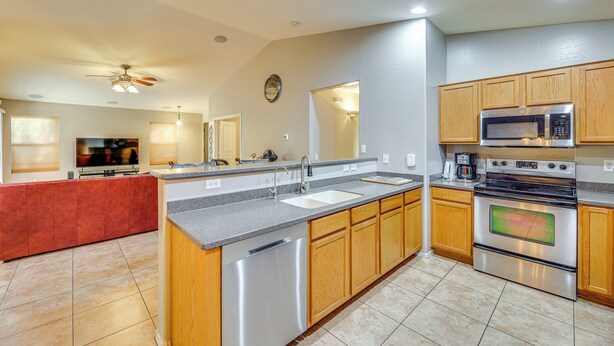 A modern kitchen with a central island, stainless steel appliances, wooden cabinets, and a large mirror. - 5 Mi to Downtown - Peaceful Home in Casa Grande (Casa Grande)