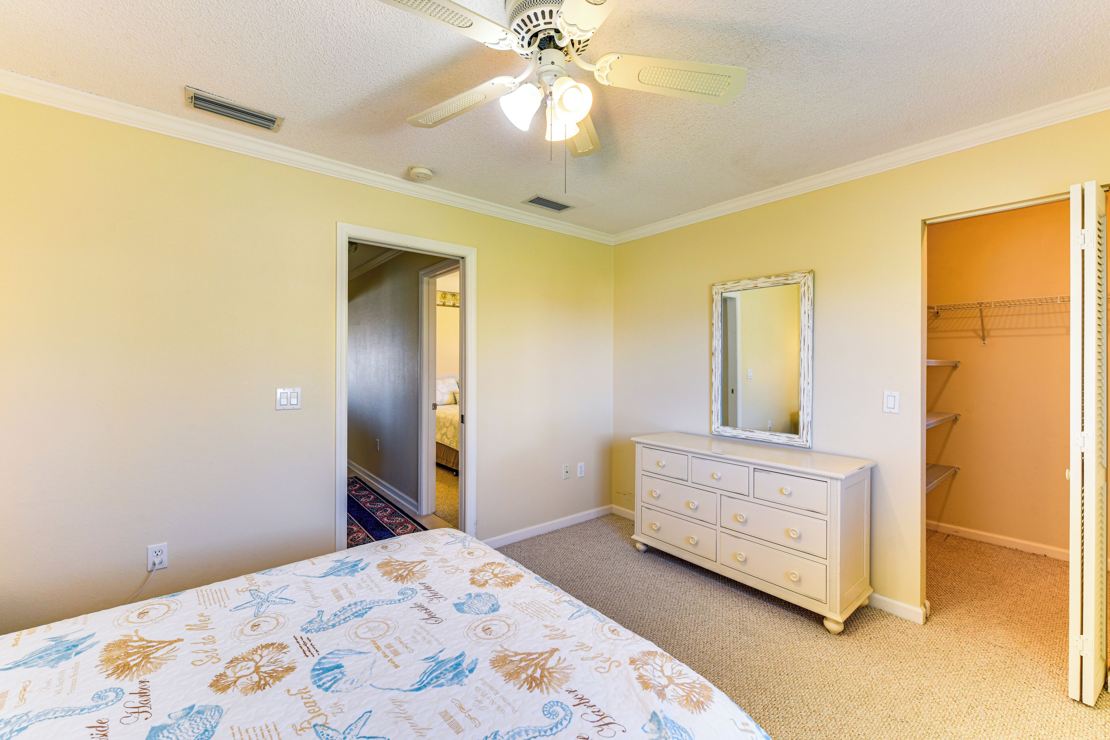 A bedroom with a bed, dresser, and a ceiling fan.