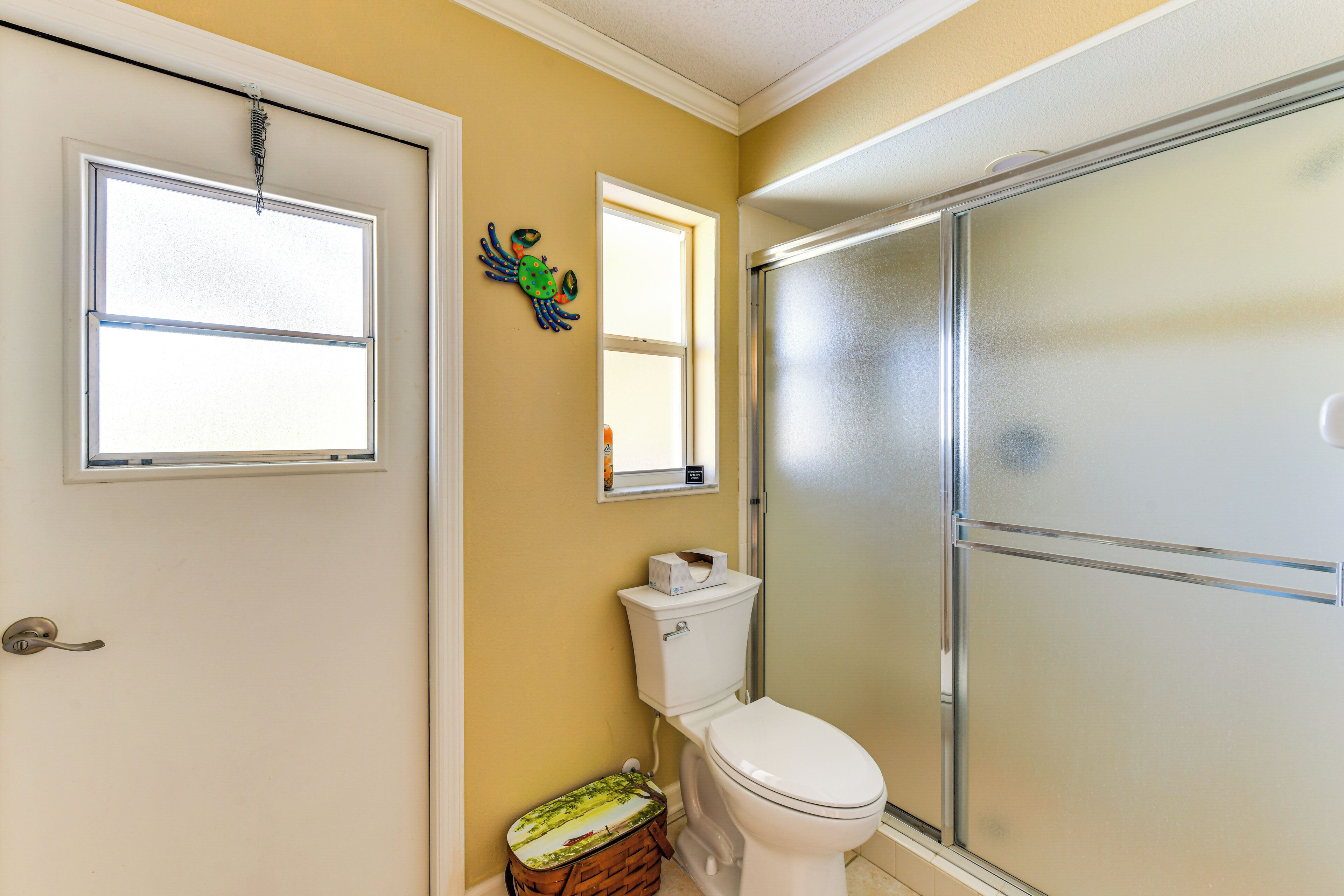 A bathroom with a toilet, a window, and a shower enclosure.