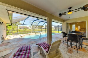 A covered outdoor area with a pool, lounge chairs, and a table. - Canal-front Home in Rotonda West Near Golf + Beach (Rotonda West)