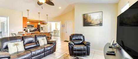 A living room with a leather sofa, a recliner, a flat-screen TV, and a ceiling fan.